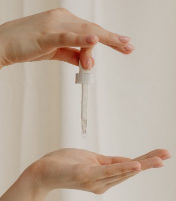 Main tenant une pipette de sérum au dessus d'une autre main