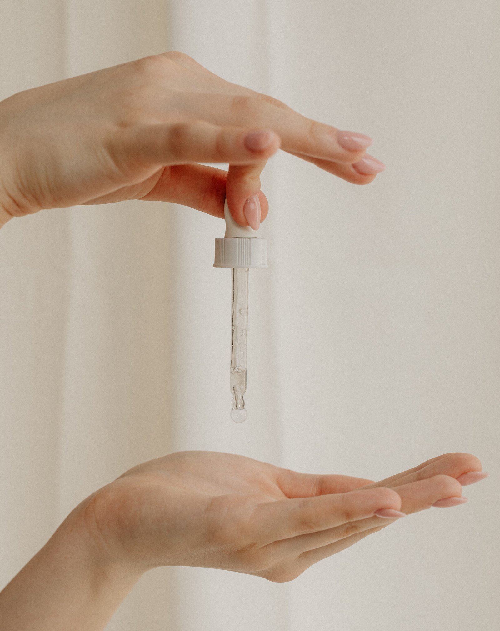 kaboompics_applying-facial-serum-for-enhanced-skin-care-32019-copie-scaled Main tenant une pipette de sérum au dessus d'une autre main